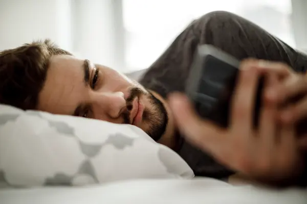 man on bed using smartphone